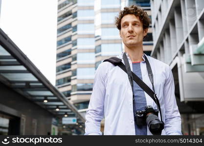 Male tourist in city. Happy male tourist in city walking with camera