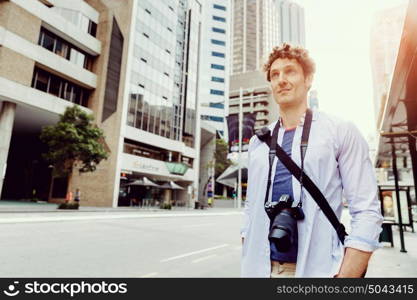 Male tourist in city. Happy male tourist in city walking with camera