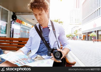 Male tourist in city. Happy male tourist in city with camera and map