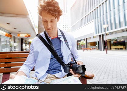 Male tourist in city. Happy male tourist in city with camera and map