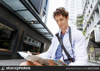 Male tourist in city. Happy male tourist in city with camera and map