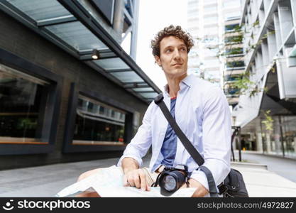 Male tourist in city. Happy male tourist in city with camera and map