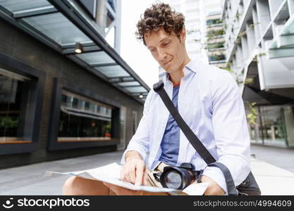 Male tourist in city. Happy male tourist in city with camera and map