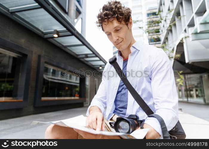 Male tourist in city. Happy male tourist in city with camera and map