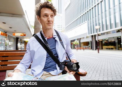 Male tourist in city. Happy male tourist in city with camera and map