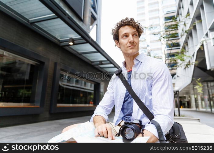 Male tourist in city. Happy male tourist in city with camera and map