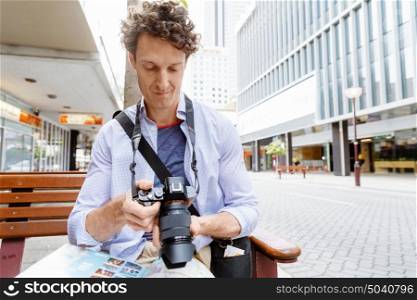 Male tourist in city. Happy male tourist in city with camera and map