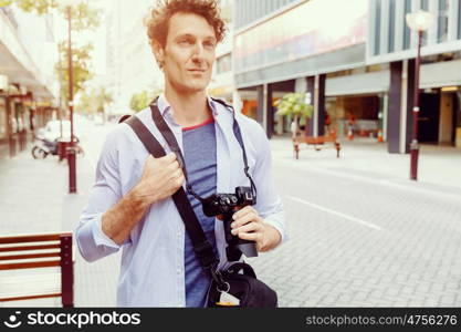 Male tourist in city. Happy male tourist walking in city with camera