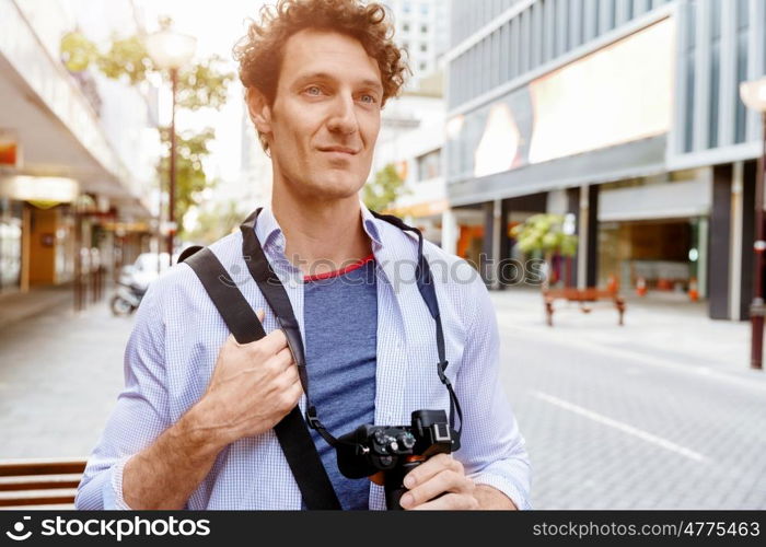 Male tourist in city. Happy male tourist walking in city with camera