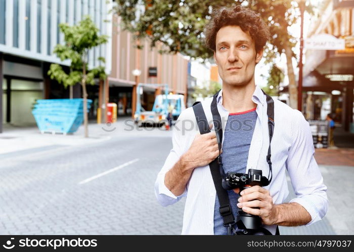 Male tourist in city. Happy male tourist walking in city with camera