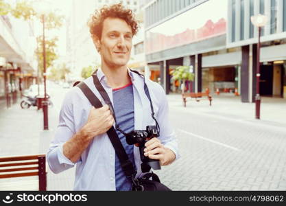 Male tourist in city. Happy male tourist walking in city with camera