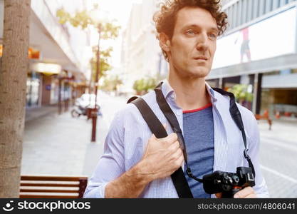 Male tourist in city. Happy male tourist walking in city with camera