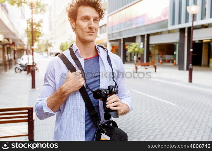 Male tourist in city. Happy male tourist walking in city with camera