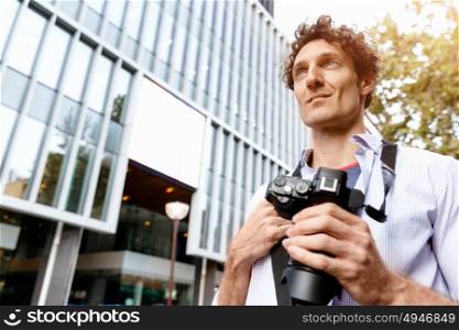 Male tourist in city. Happy male tourist walking in city with camera