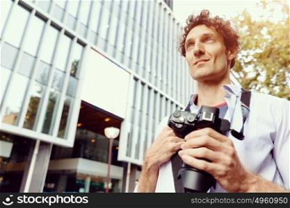 Male tourist in city. Happy male tourist walking in city with camera
