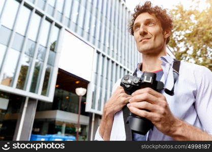 Male tourist in city. Happy male tourist walking in city with camera