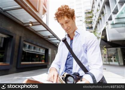 Male tourist in city. Young male tourist in city with camera and map