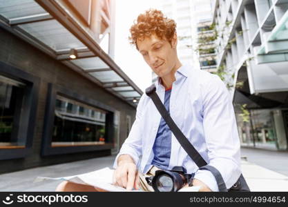 Male tourist in city. Young male tourist in city with camera and map