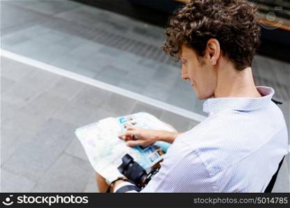 Male tourist in city. Young male tourist in city with camera and map