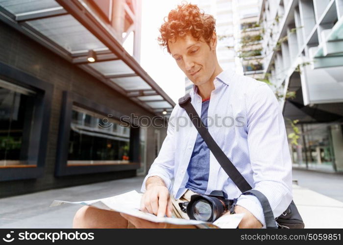 Male tourist in city. Young male tourist in city with camera and map