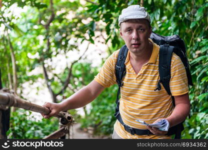 male tourist with a backpack in the jungle resting