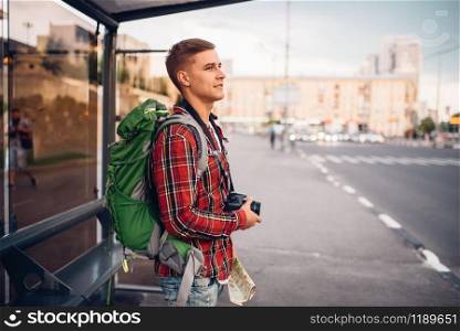 Male tourist with backpack at bus stop. Summer travelling, hike adventure over sightseeing, city walking