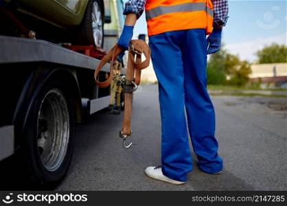 Male tow truck assistant holding belts for car fastening for safety transportation. Closeup shot. Male tow truck assistant holding fastening belts