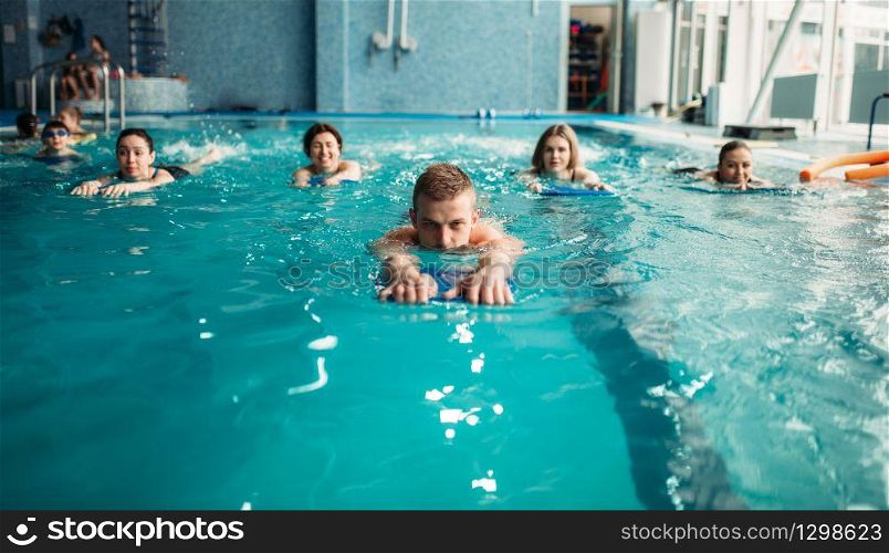 Male trainer swims with female aqua aerobics group on workout in swimming pool. Water sport. Male trainer swims with female aqua aerobics group