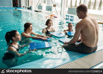 Male trainer works with female aqua aerobics group on workout in swimming pool. Water sport