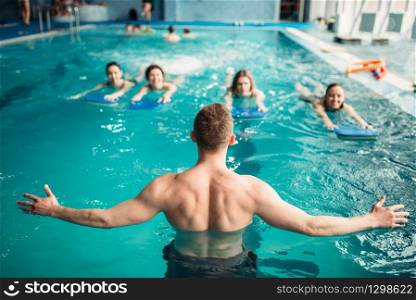 Male trainer works with female group on workout in swimming pool. Aqua aerobics training, water sport