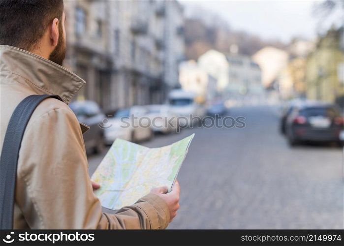 male traveler holding map hand finding way city street