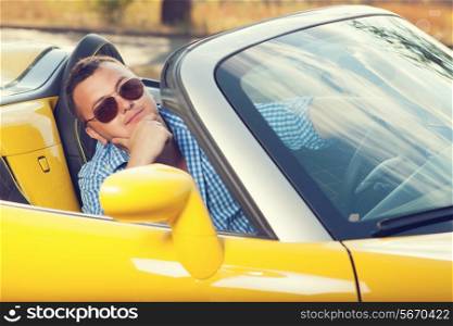 Male trendy model posing in yellow convertible car. Sunglasses. checkered shirt