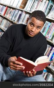 Male University student reading in library, portrait