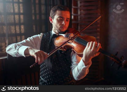 Male violinist playing classical music on violin. Fiddler man with musical instrument. Male violinist playing classical music on violin