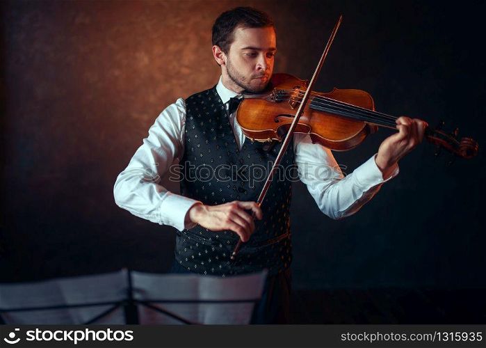 Male violinist playing classical music on violin. Fiddler man with musical instrument. Male violinist playing classical music on violin