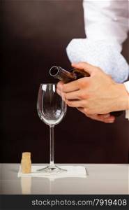 Male waiter or butler serving pouring white wine into glass.