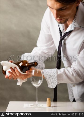 Male waiter or butler serving pouring wine into glass.