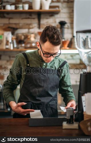 Male waiter prepares the check in coffee house. Coffee house, restaurant or bars concept.. Male waiter prepares the check in coffee house.