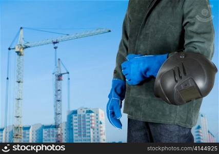 male welder closeup with welding equipment on building background