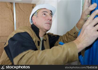 male worker bundling pipework on interior building site