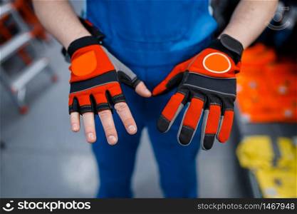 Male worker hands in protective gloves in tool store. Choice of professional equipment in hardware shop, instrument supermarket. Male worker hands in protective gloves, tool store