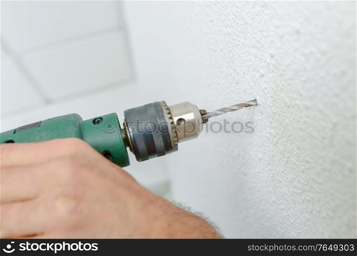 male worker is drilling a hole