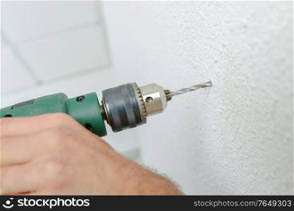male worker is drilling a hole