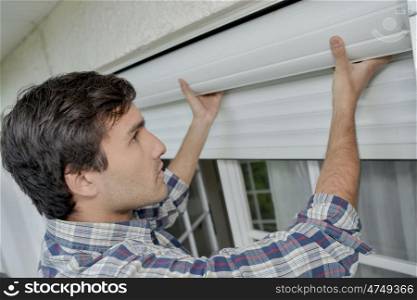 male worker is fitting window shutters