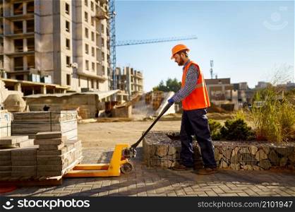 Male worker making concrete at construction site. Builder using shovel loading mixer with sand. Male worker making concrete at construction site