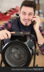 male worker on the phone while fixing a heater