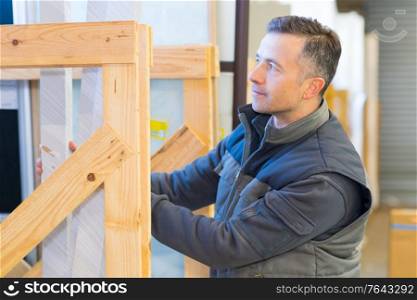 male worker stacking materials in wooden display frame