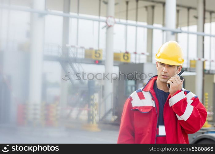 Male worker using walkie-talkie in shipping yard