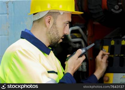 male worker wearing reflective clothing using walkie talkie