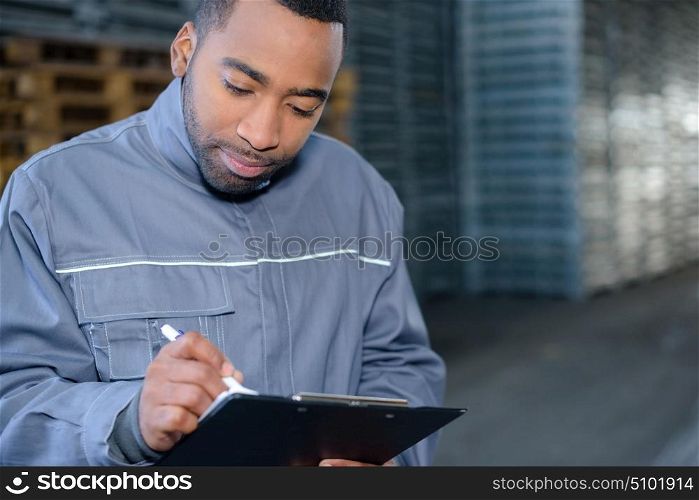 Male worker writing on clipboard